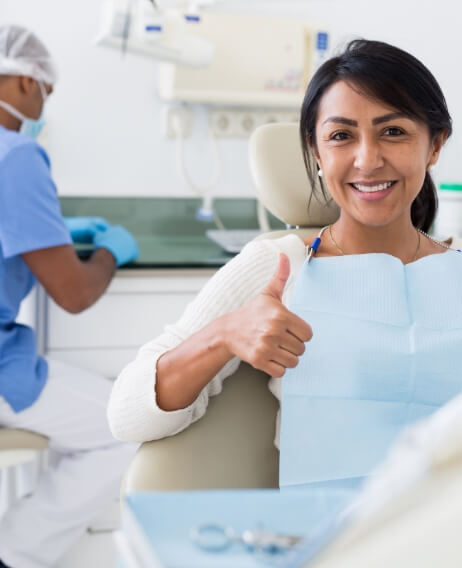 Woman in dental chair smiling and giving thumbs up