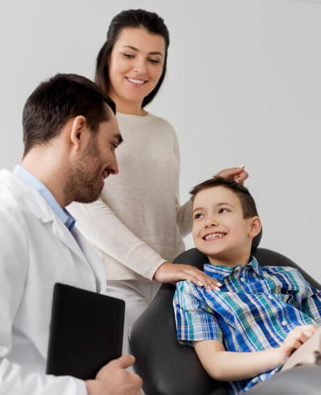 Young boy in dental chair smiling at his dentist