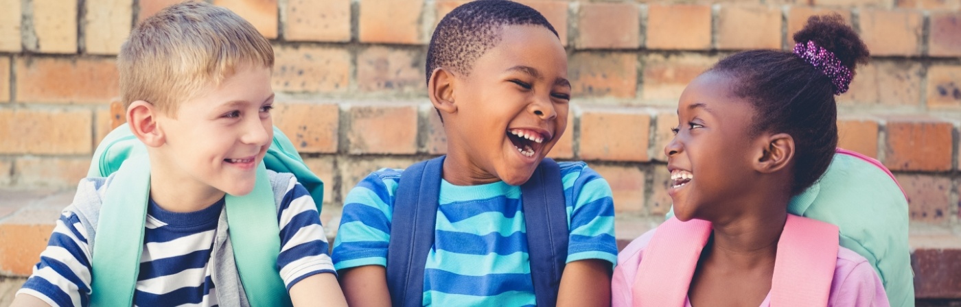 Three kids with backpacks laughing together after seeing childens dentist in Dallas