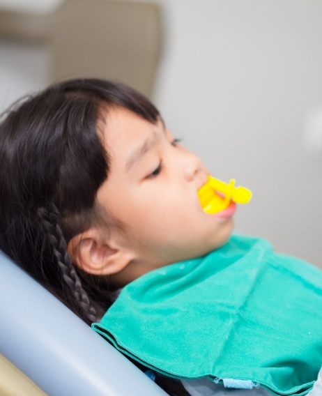 Child in dental chair with fluoride on their teeth