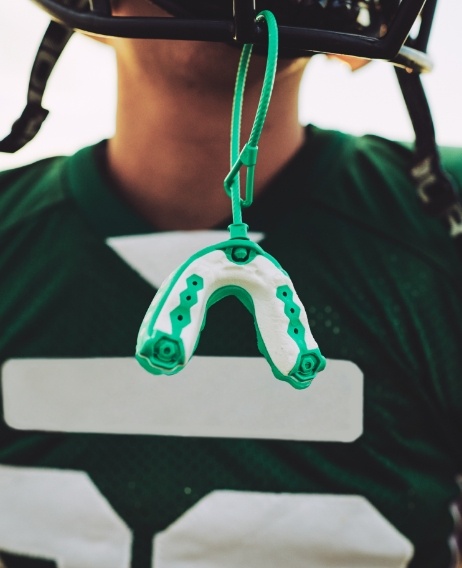 Football player with a mouthguard hanging from their helmet