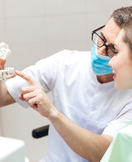 a dentist showing their patient how dental implants work