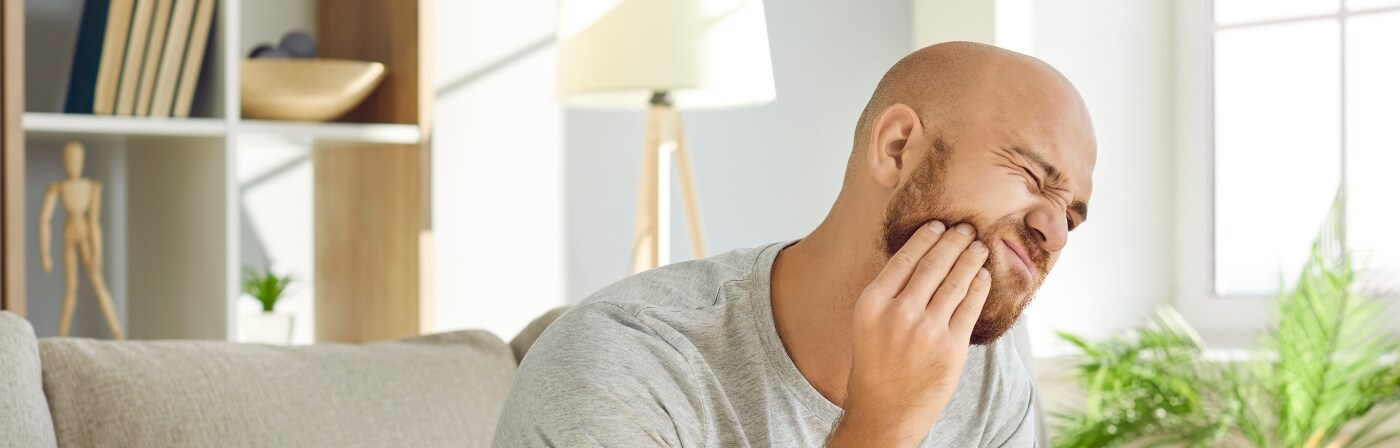 Man holding his cheek in pain before tooth extractions in Dallas