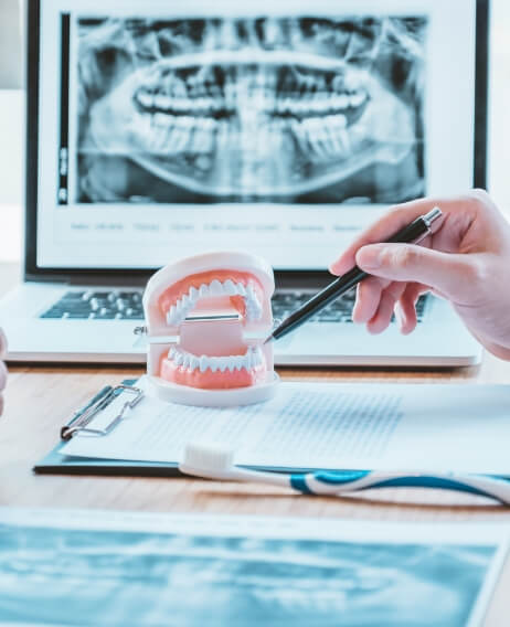 Dentist sitting at desk with clipboard and model of the teeth