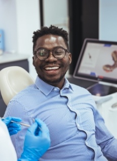 Man in dental chair smiling at his dentist