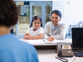 Mother and daughter at reception desk in dental office