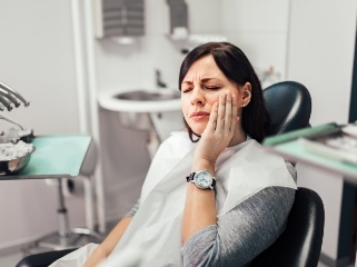 Dental patient holding her cheek in pain