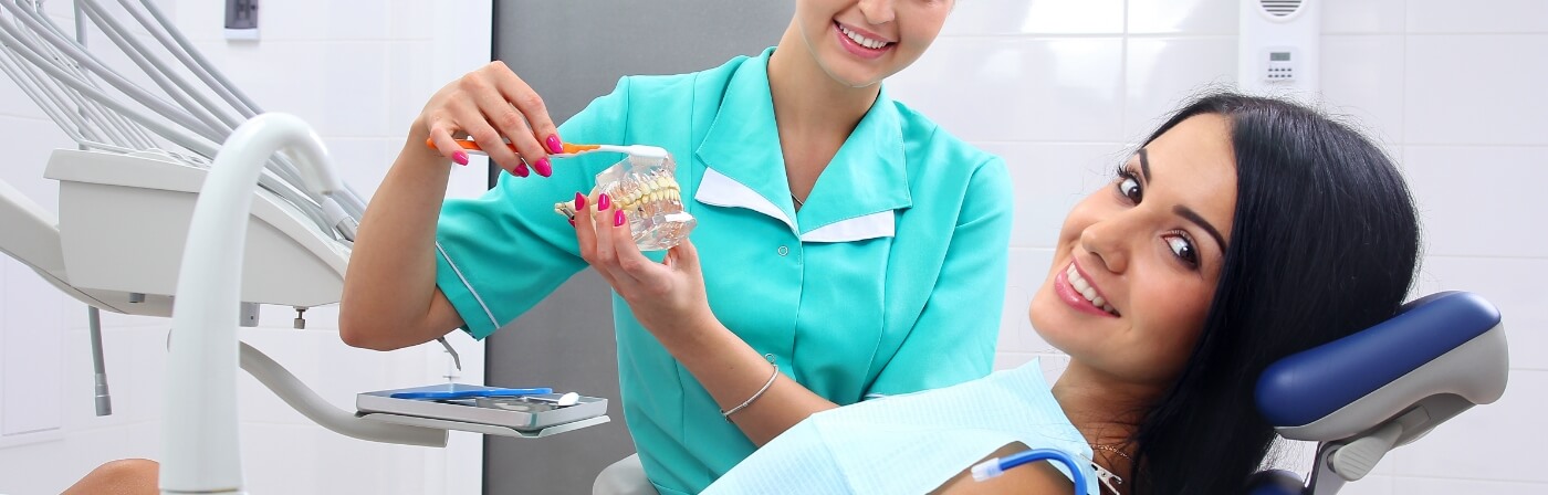 Smiling woman sitting in dental chair after replacing missing teeth in Dallas