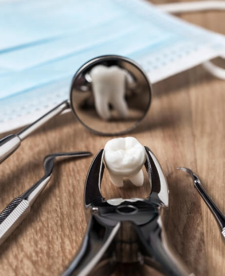 Dental forceps on a desk holding an extracted wisdom tooth